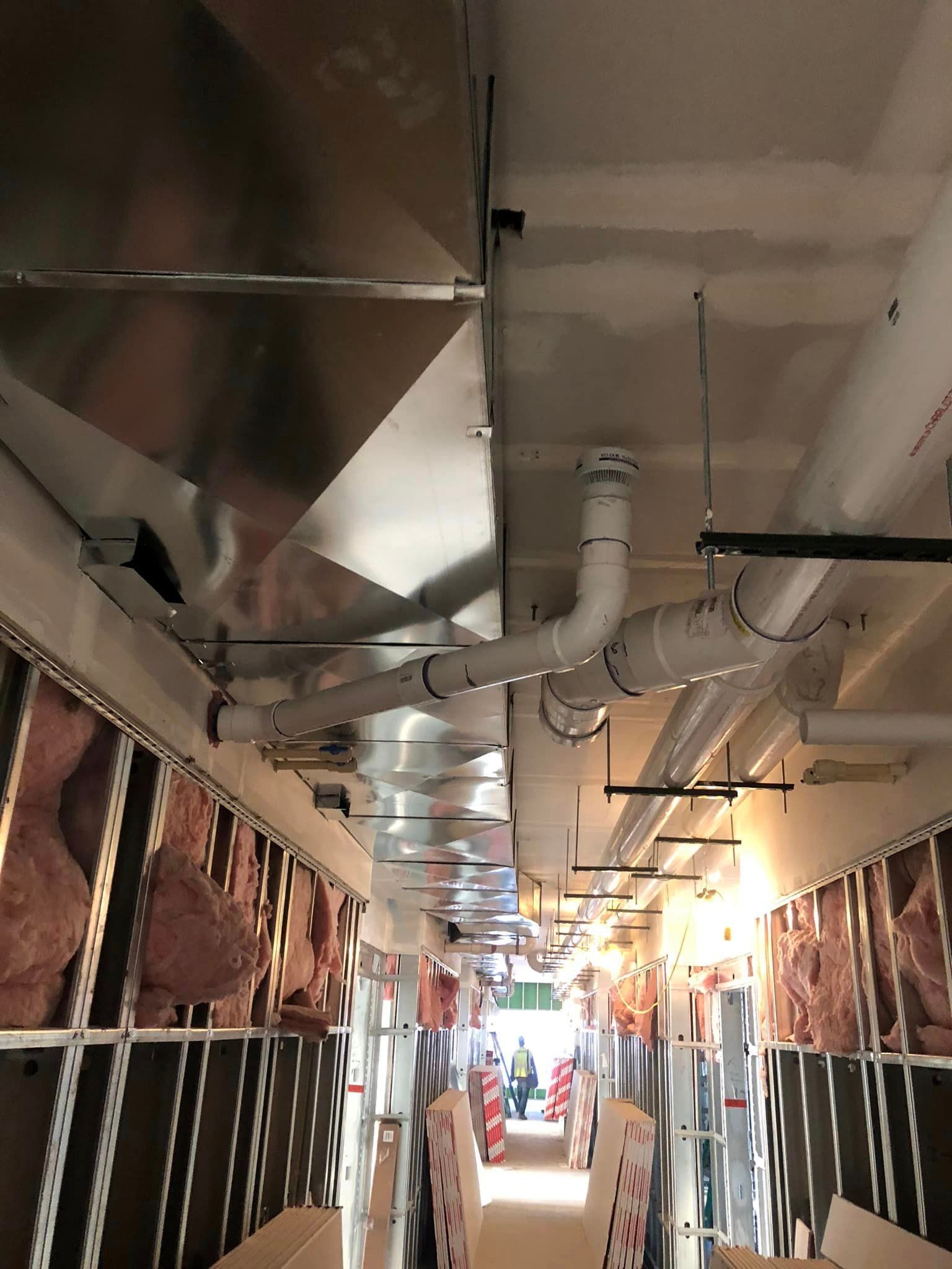 A long hallway with a lot of pipes hanging from the ceiling
