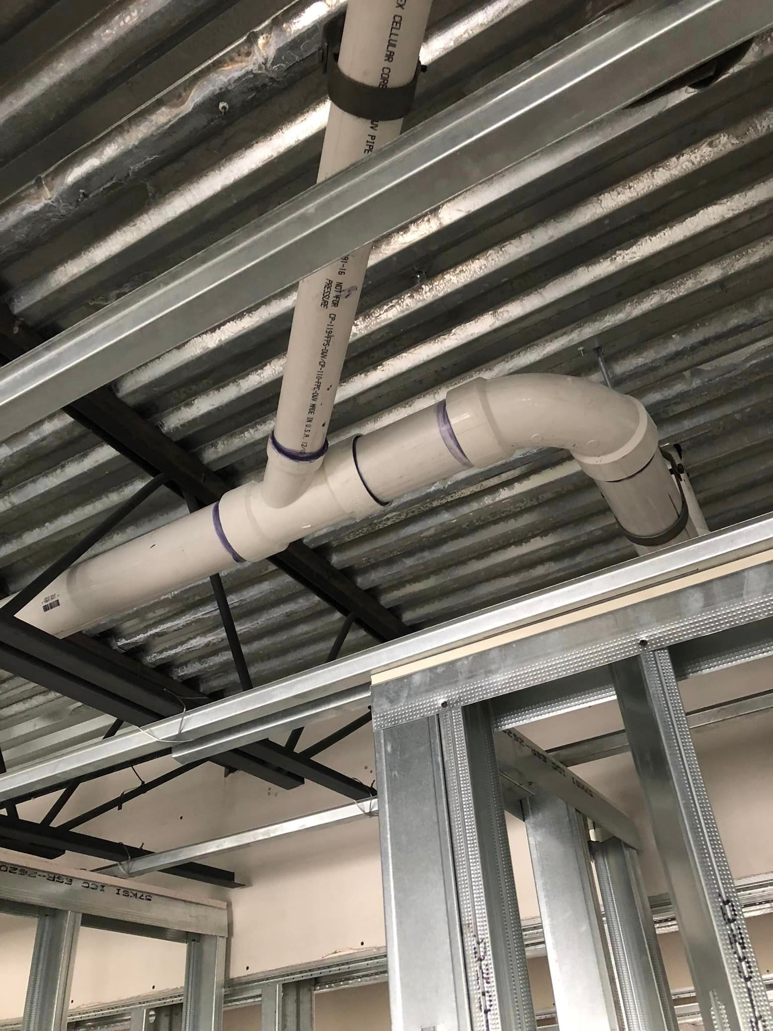 A pipe is hanging from the ceiling of a building under construction.