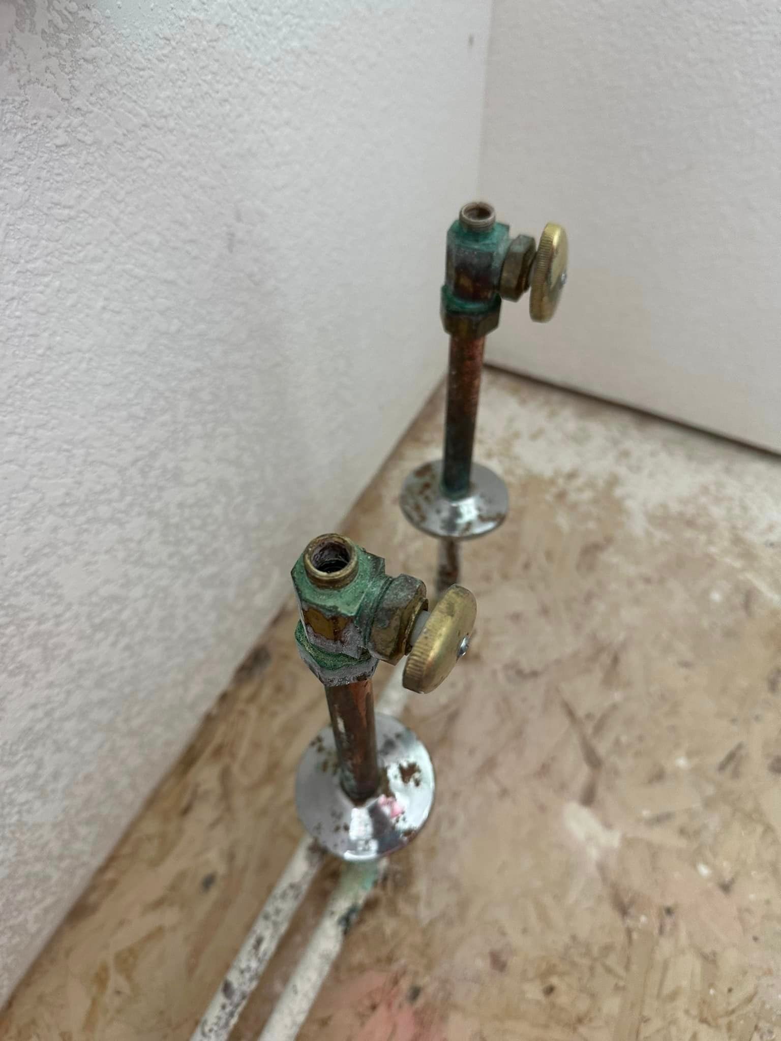 A pair of faucets are sitting on a wooden floor next to a wall.