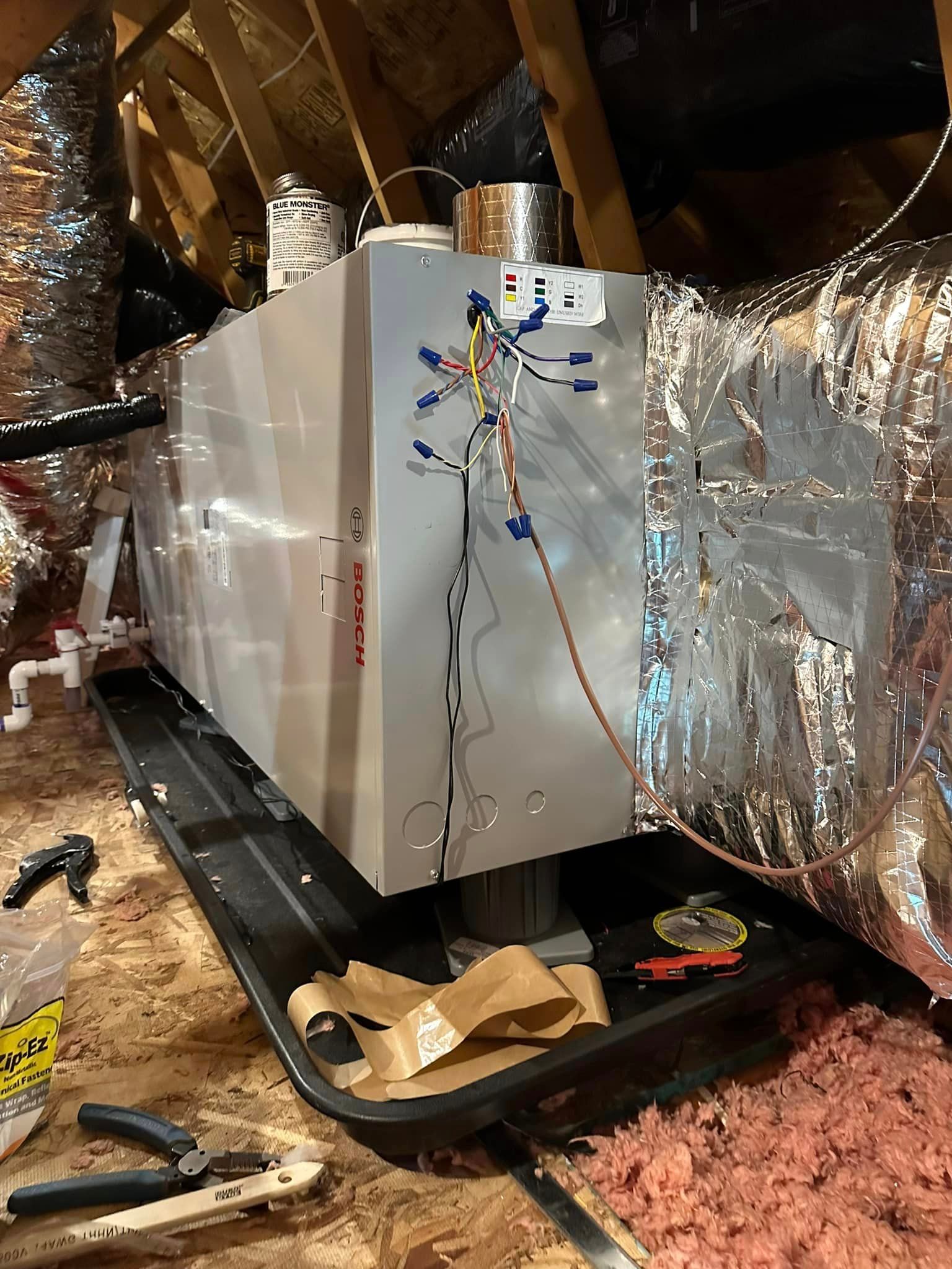 A heater is sitting on top of a tray in an attic.