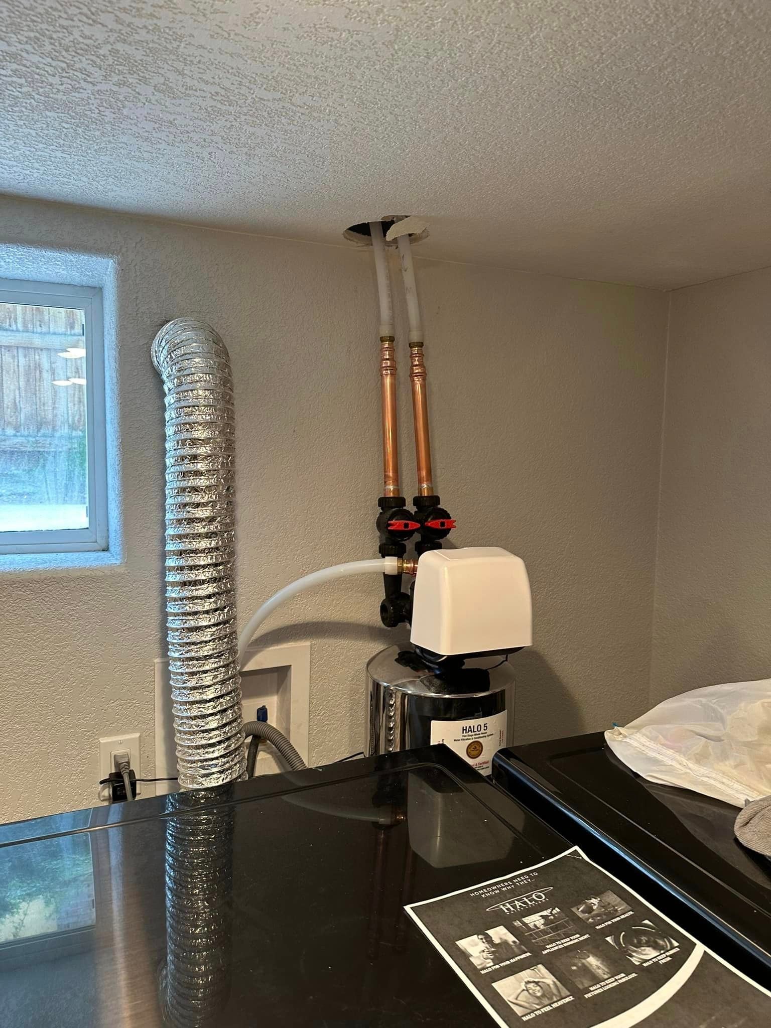 A stainless steel stove top oven with a copper pipe coming out of the ceiling.