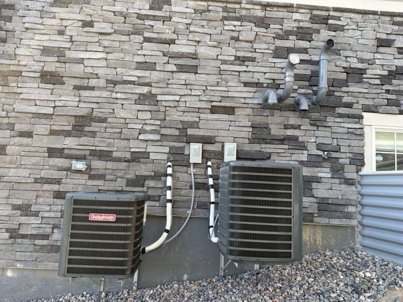 Two air conditioners on the side of a brick building