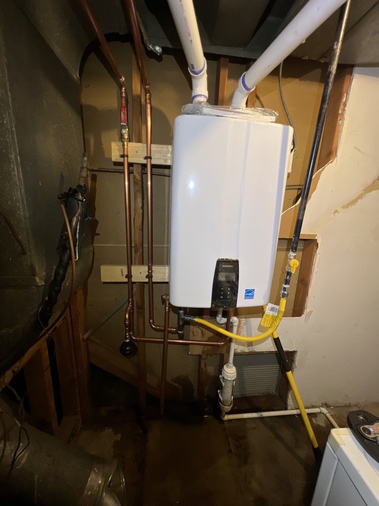 A white water heater is hanging from the ceiling in a basement.