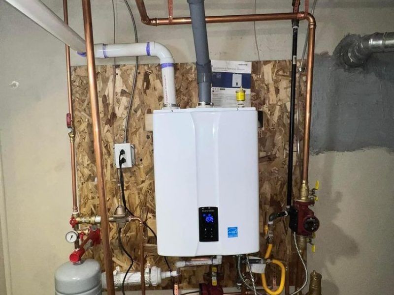 A white water heater is hanging from the ceiling in a basement.