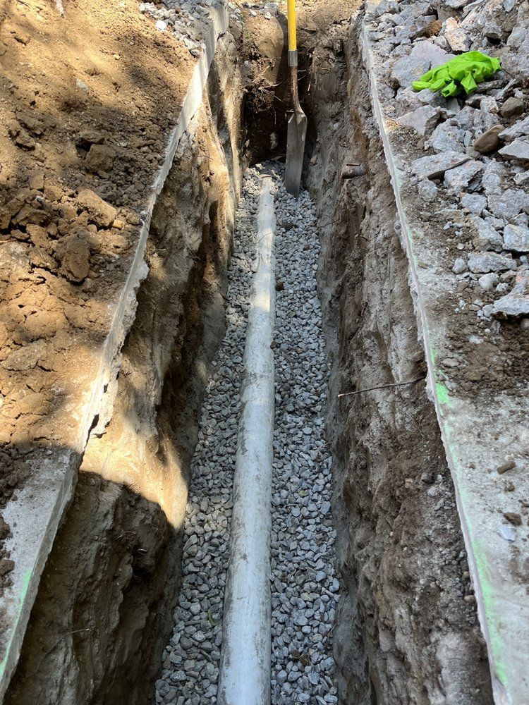 A pipe is being installed in a trench with a shovel.