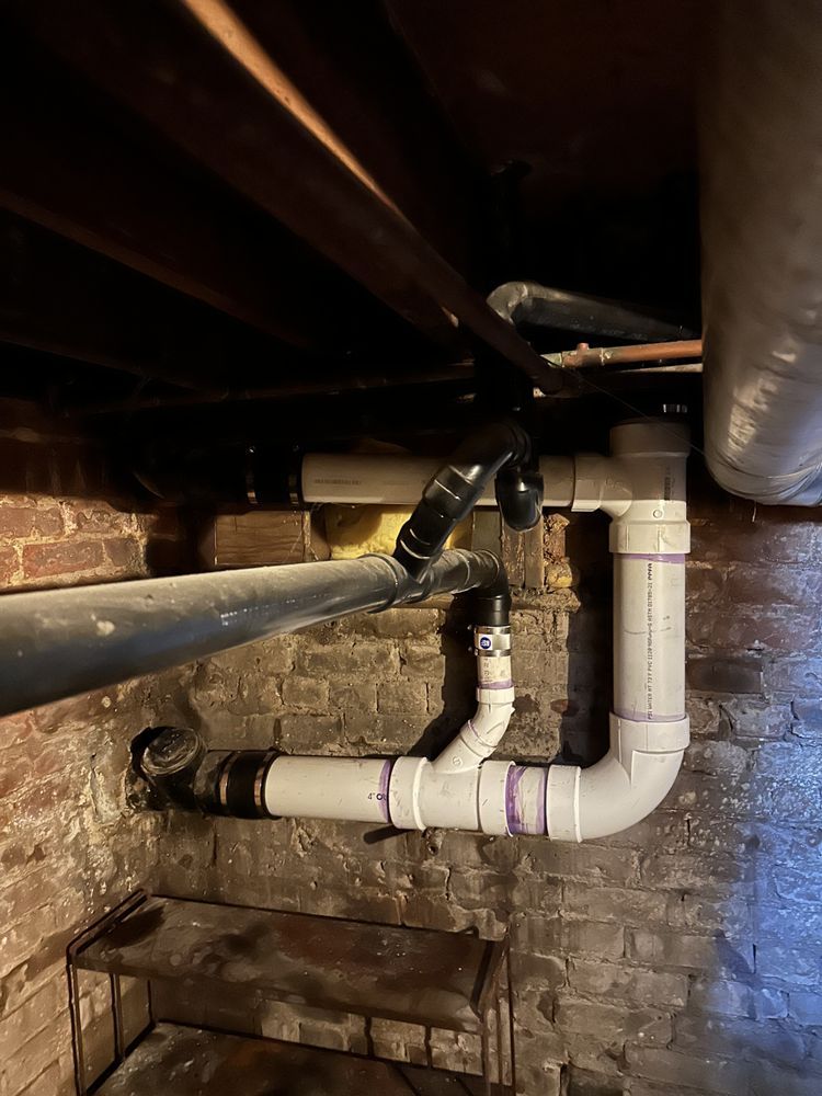 A brick wall with a bunch of pipes coming out of it