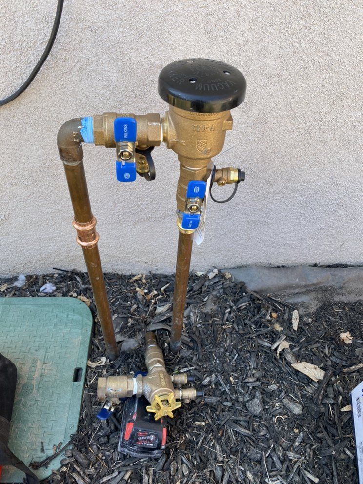 A hose with blue valves is sitting on the ground next to a wall.