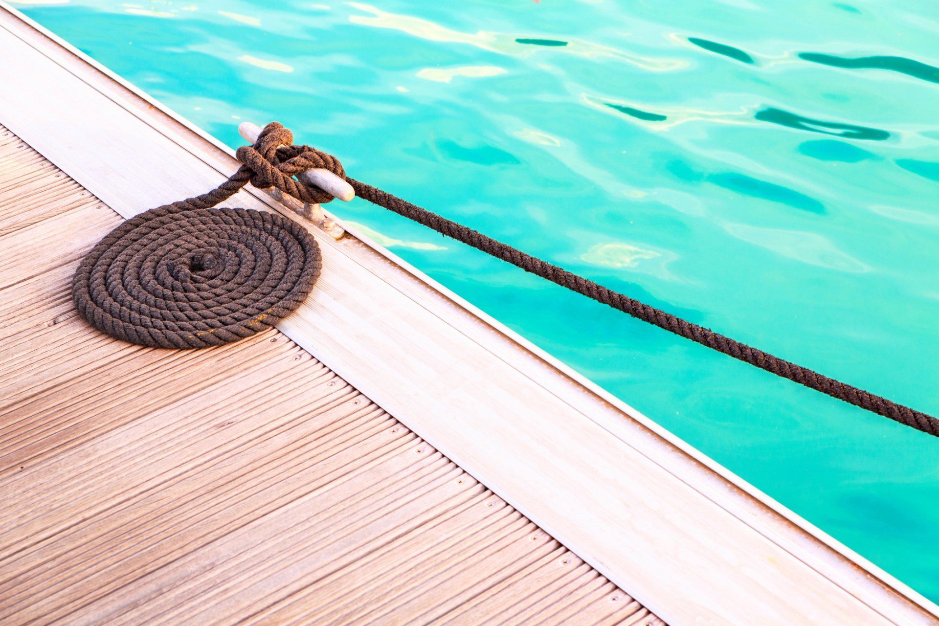A rope is tied to a wooden deck next to a swimming pool.