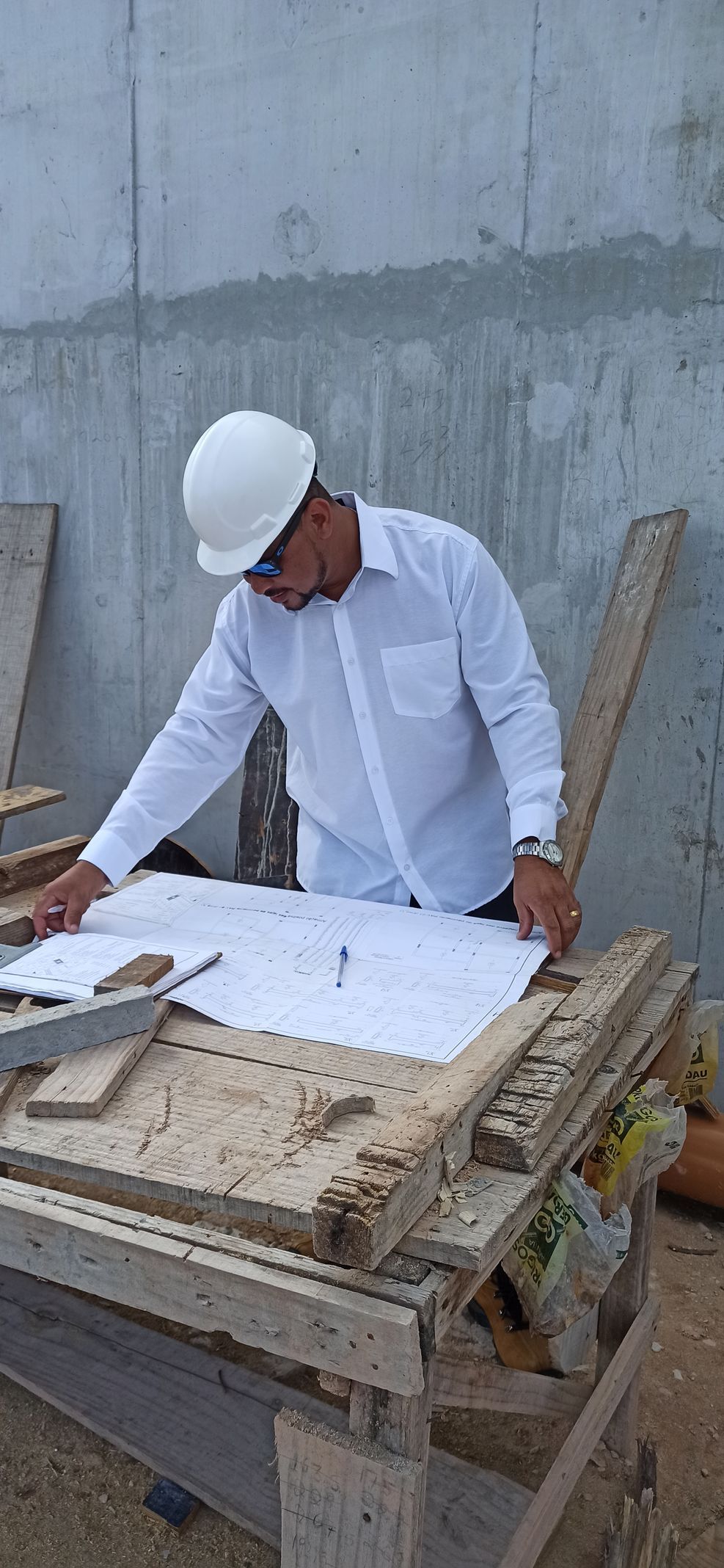 Um homem usando um capacete está olhando para uma planta sobre uma mesa.