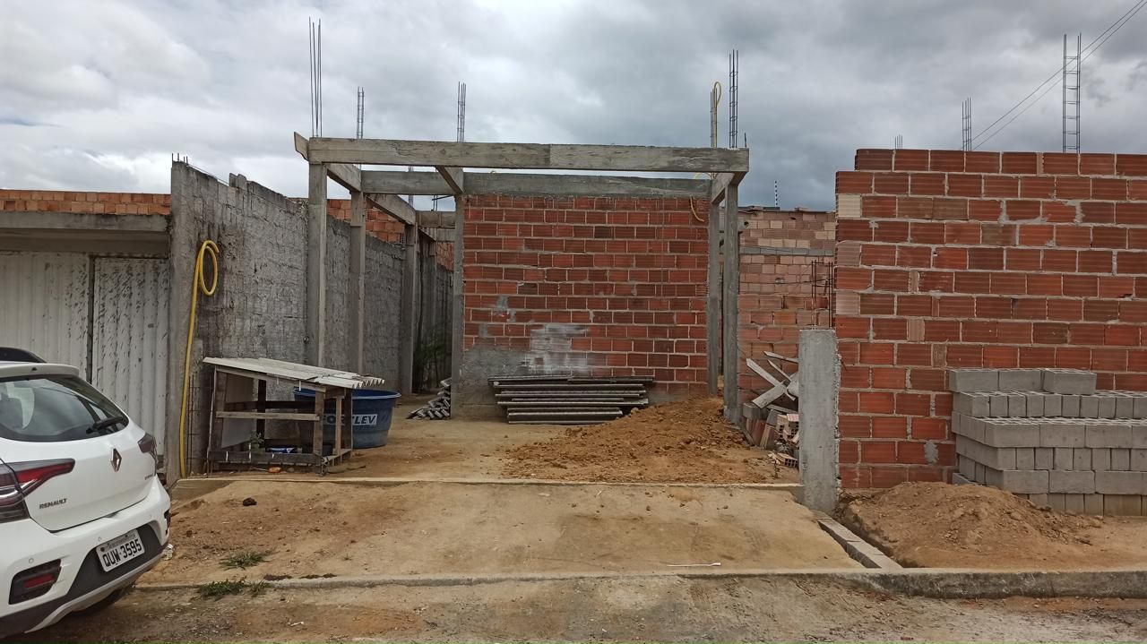 Um carro está estacionado em frente a um prédio de tijolos em construção.