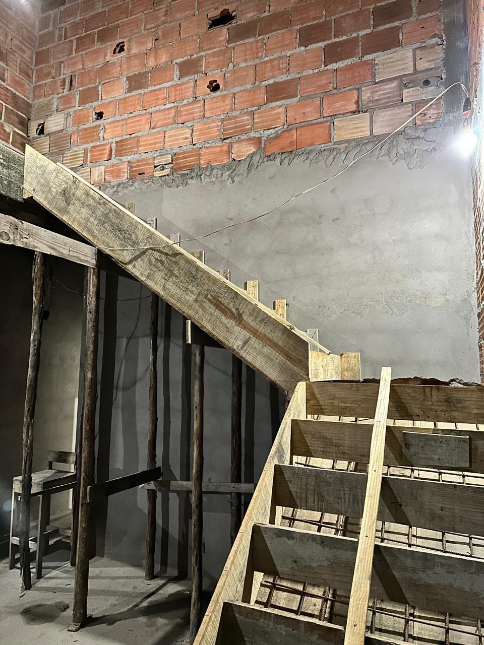 Uma escada está sendo construída em uma sala com uma parede de tijolos.