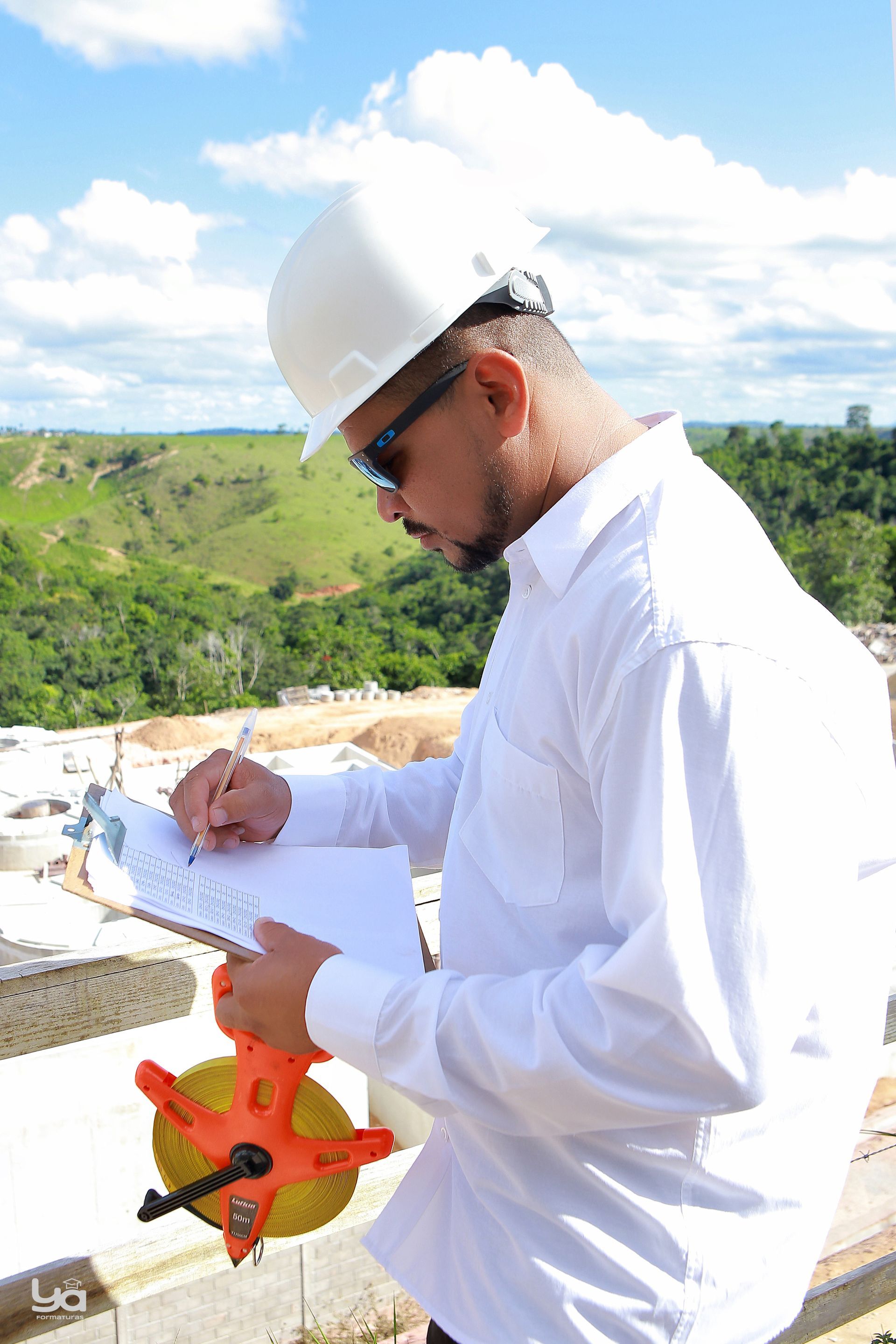 Um homem usando um capacete está escrevendo em uma prancheta.