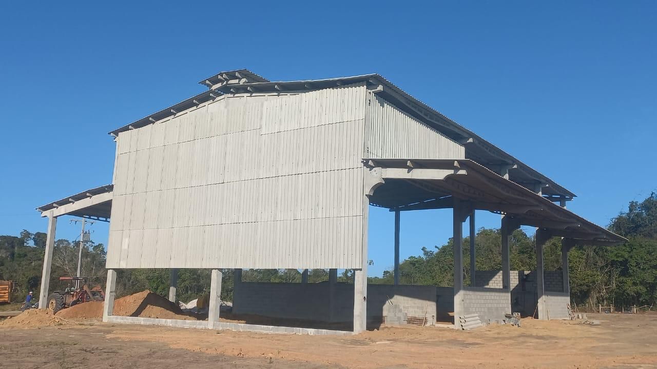 Um grande edifício branco está situado no meio de um campo de terra.