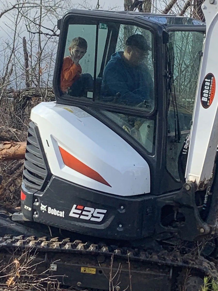 Man and Kid Inside Small Tractor — Appomattox, VA — Taylor’s Septic Service Inc