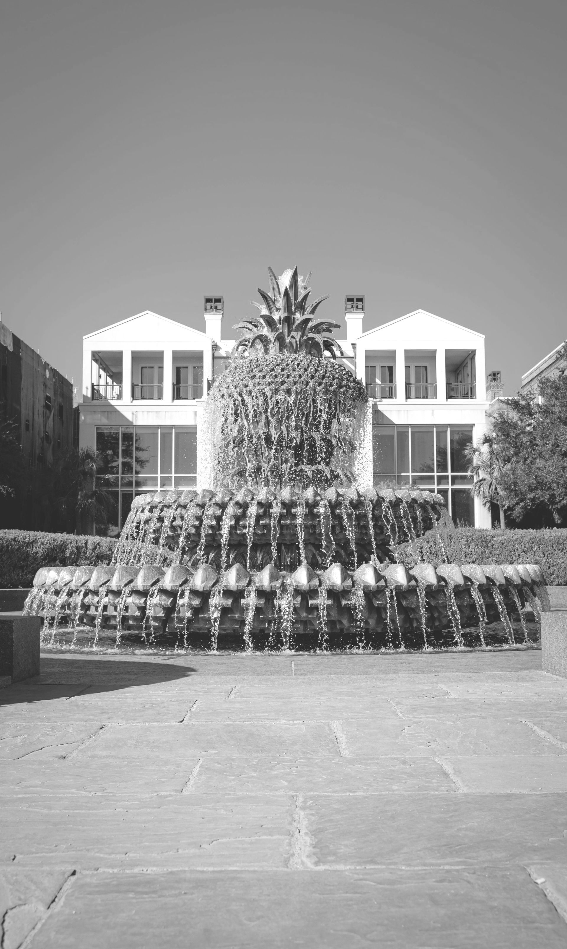 A black and white photo of a fountain in front of a house.
