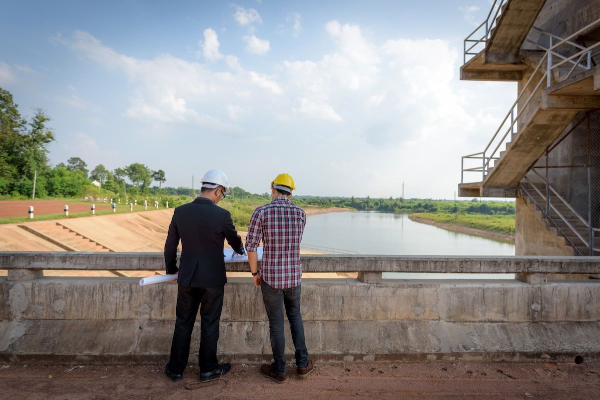 Two Men Are Standing on A Bridge Looking at A River — MDK Mini Excavator - Dingo & Tipper Hire in Bauple, QLD