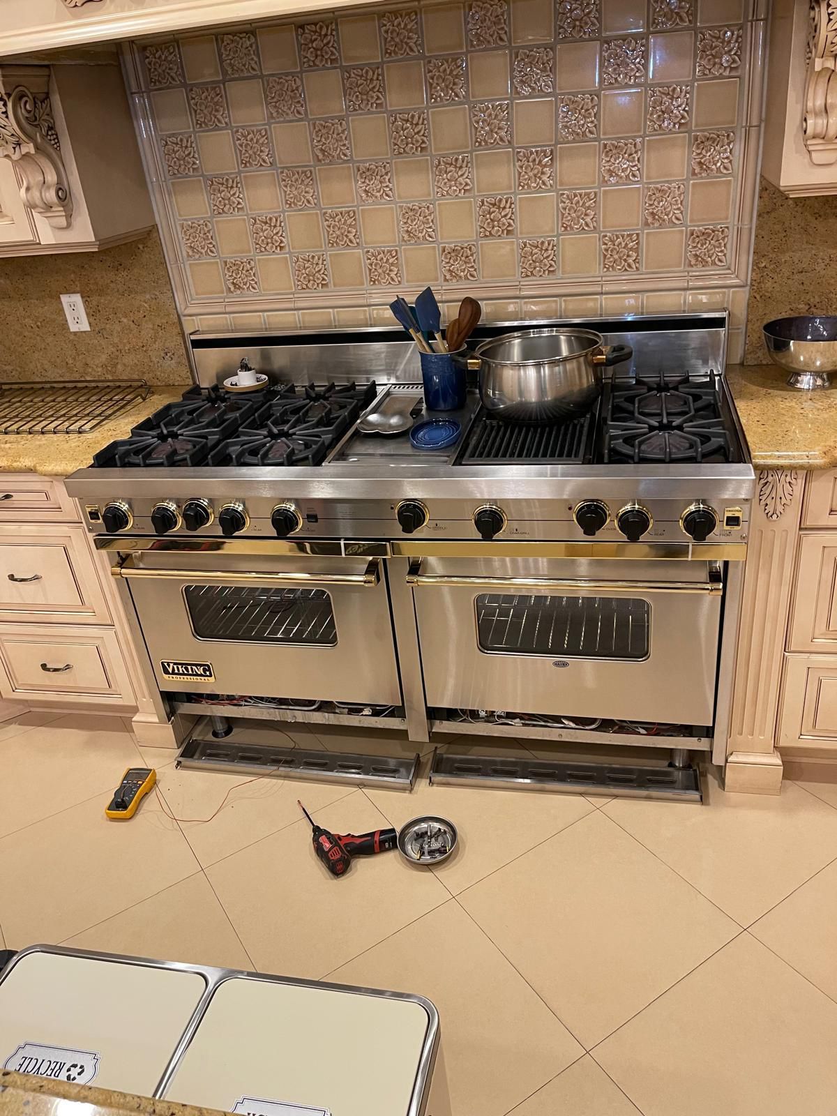 Stainless steel Viking range in a kitchen with tiled backsplash and cream cabinets.