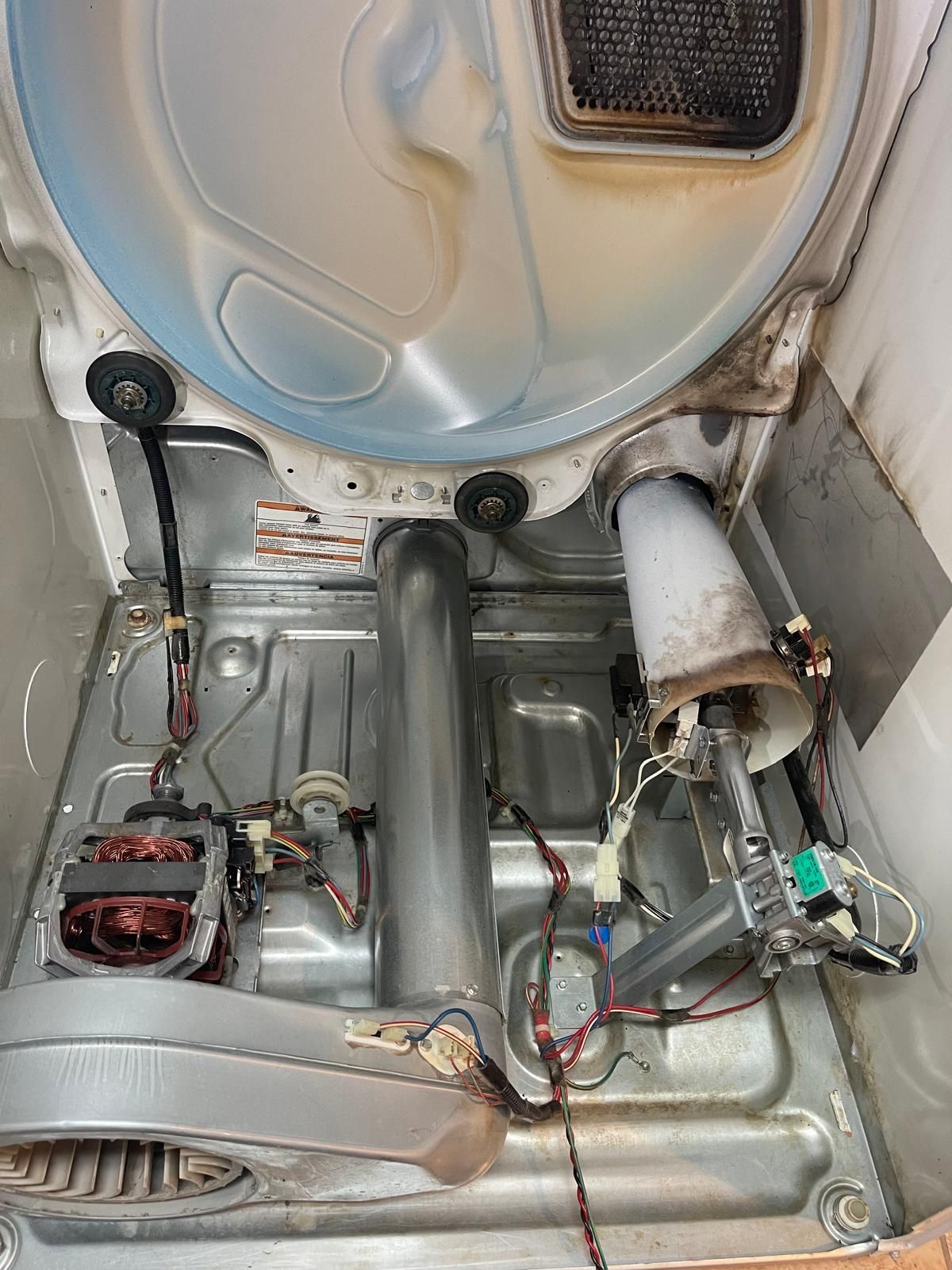 Inside of a dryer, showing components like motor, drum, ductwork, lint filter, and wiring.