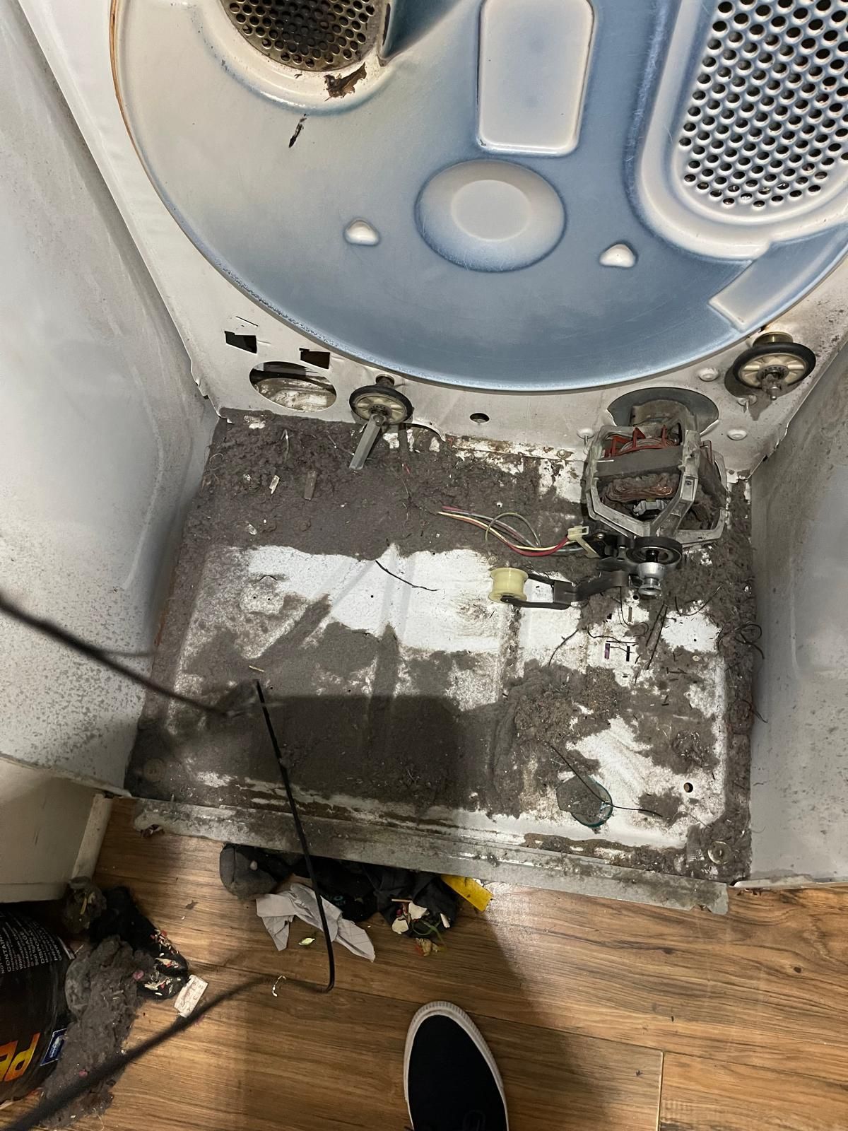 Inside of dryer with a thick layer of lint and debris, highlighting the need for cleaning.