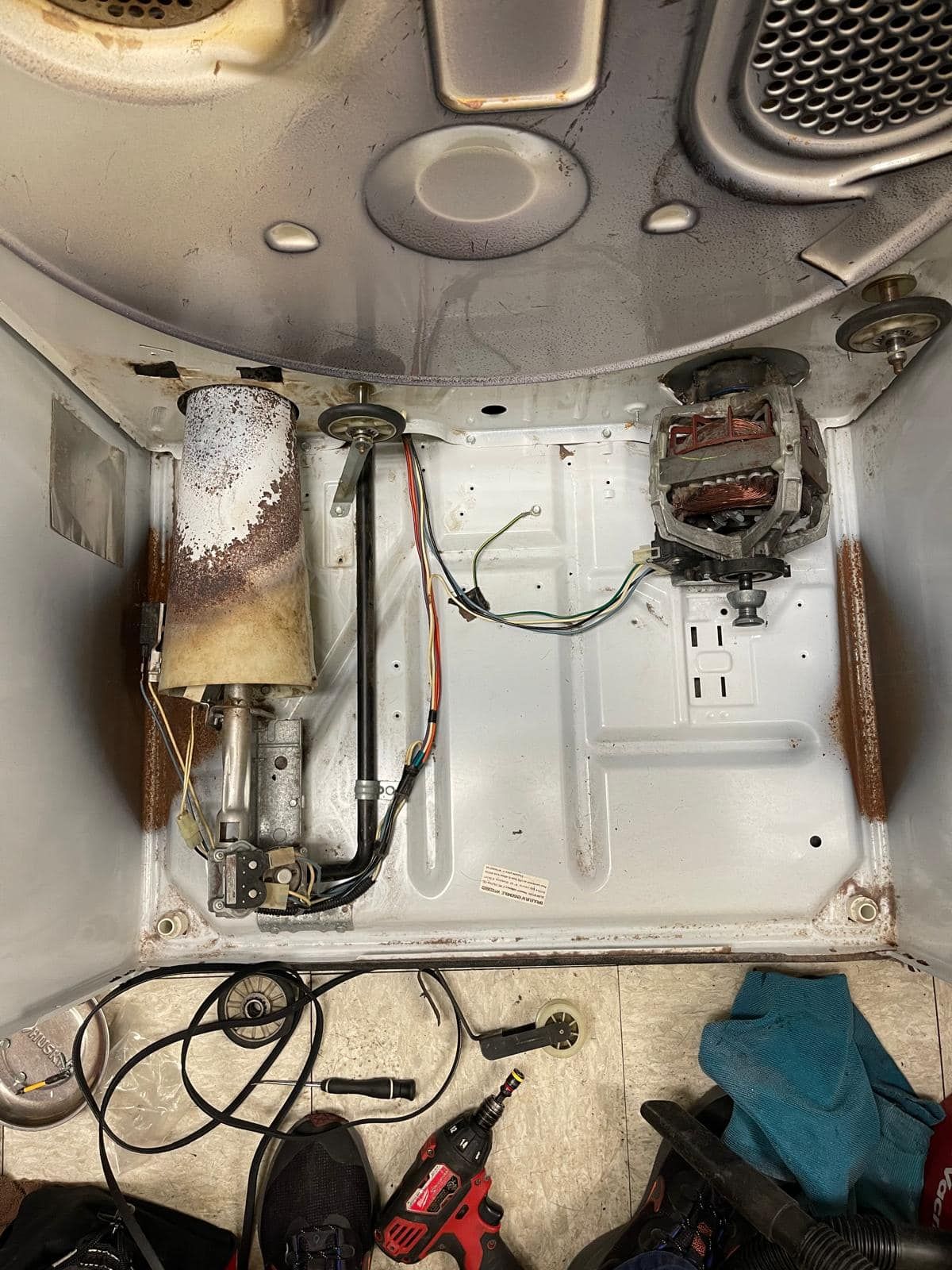 Inside of a dryer, motor, heating element, wires, and other components exposed.