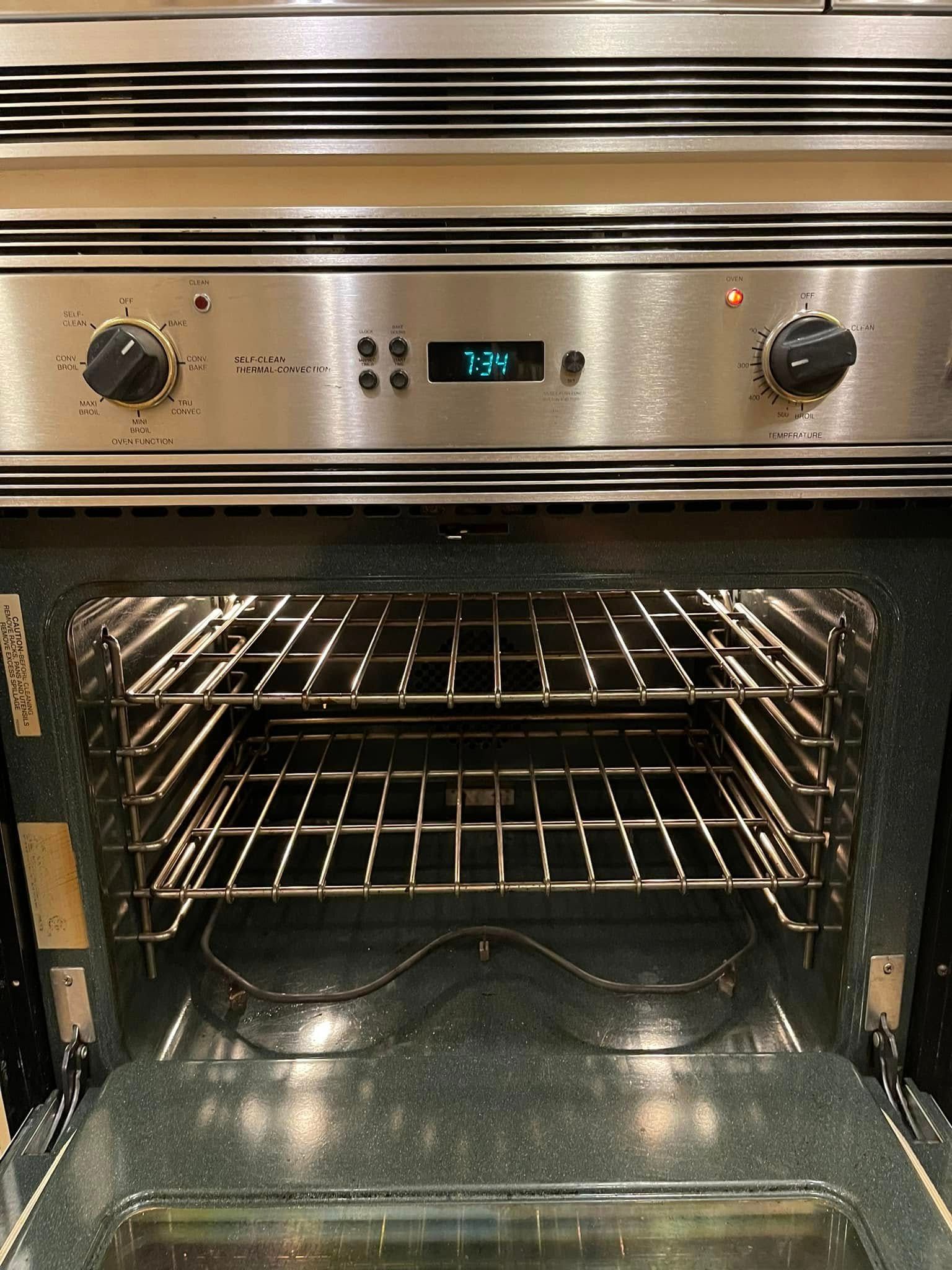 Stainless steel oven with open door; interior with racks.