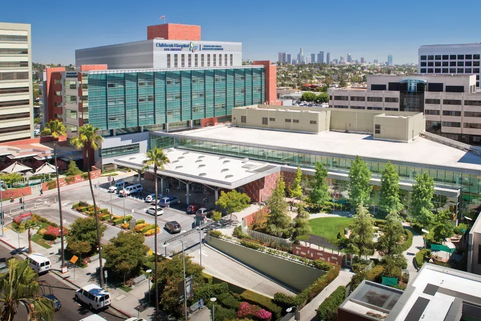 Cedars-Sinai Medical Center in Los Angeles. Large modern hospital building with greenery and city skyline in background.
