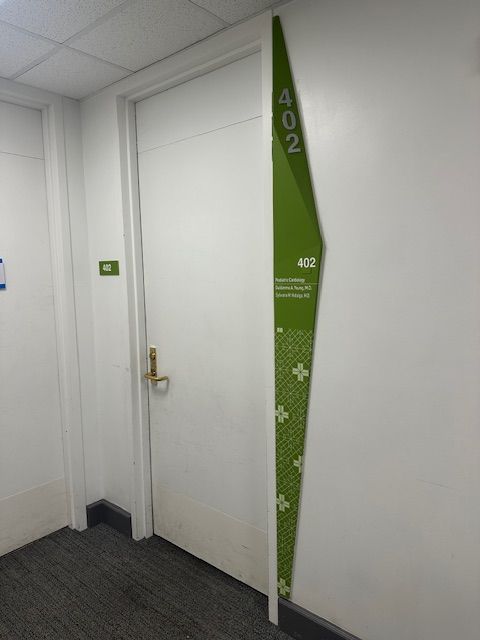 White door with gold handle and green signage indicating room 402. Dark gray carpet.