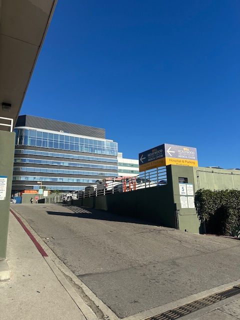 Entrance to a hospital parking structure, with signage and a modern building in the background against a blue sky.