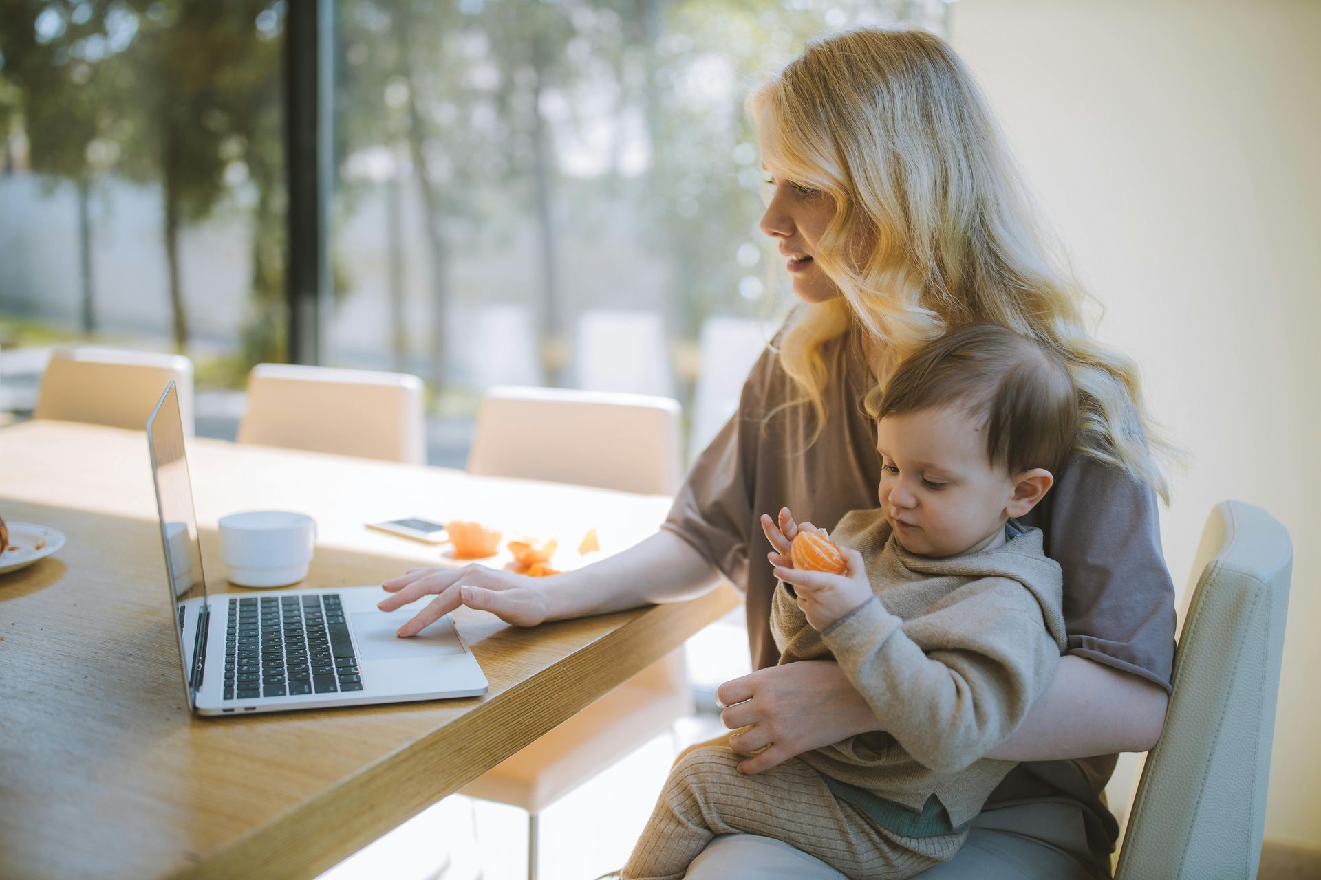 Woman sitting on a chair with a child on her lap. The woman in typing on a computer.