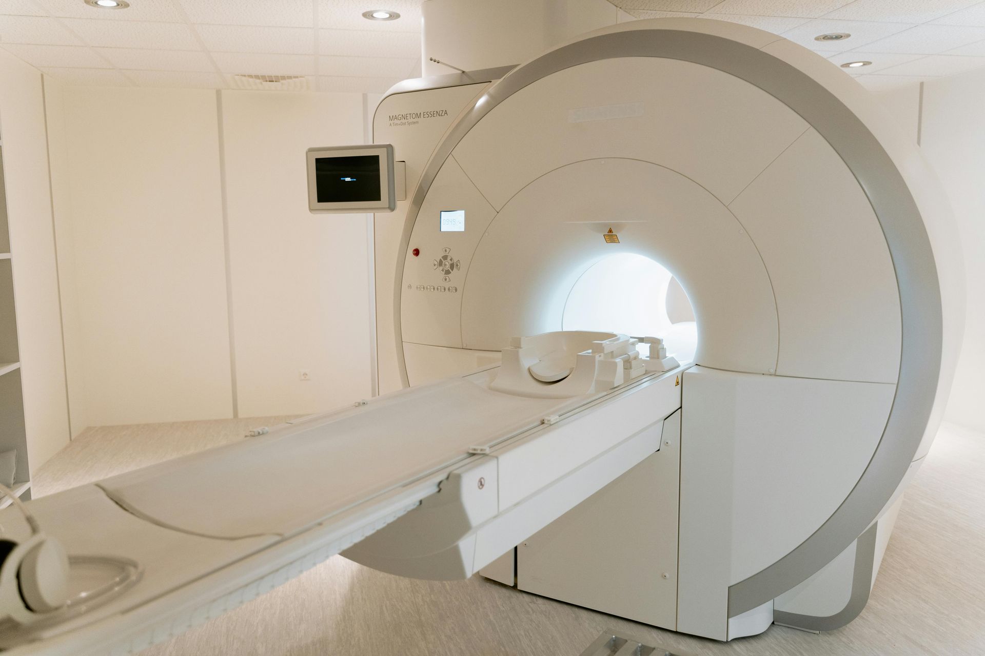 MRI machine in a white room with a patient bed extended.