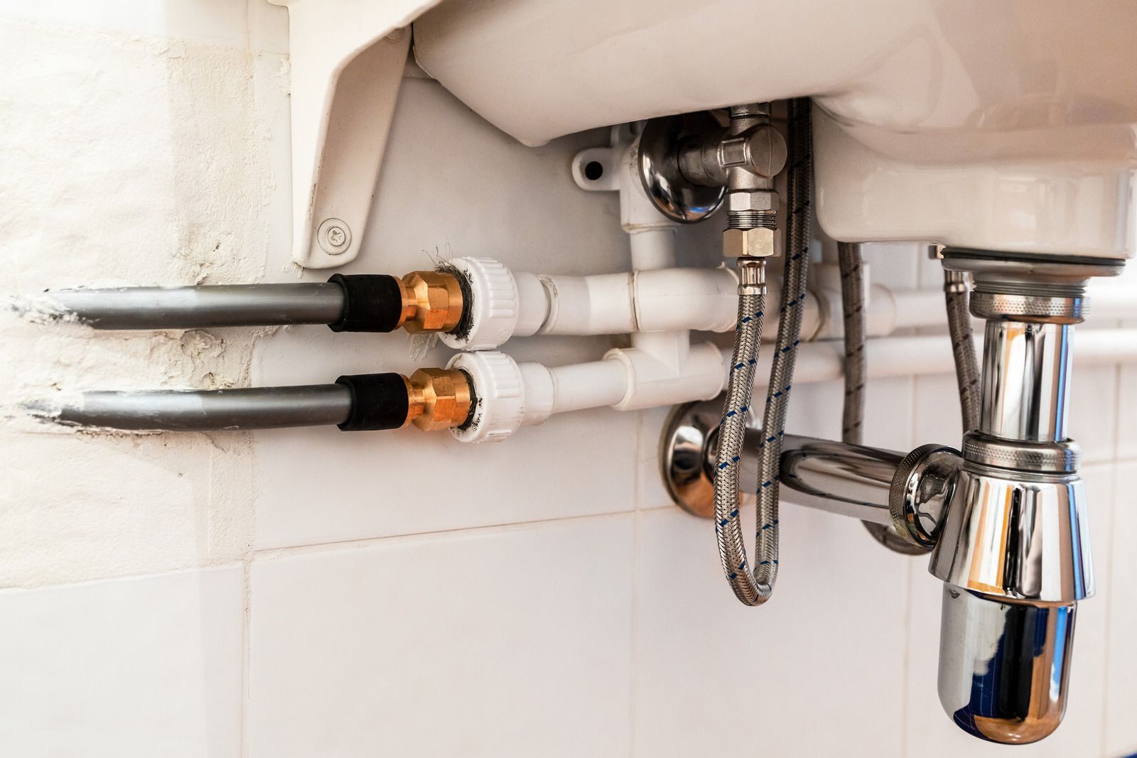 A close up of a sink with pipes attached to it.