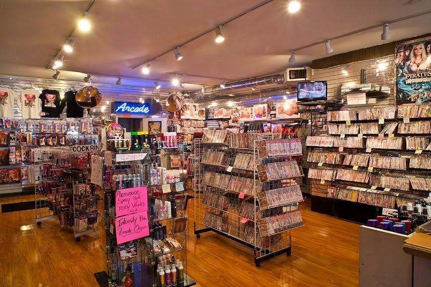 Comic shop interior with rows of manga, anime merchandise, and a pink sale sign on wood floors