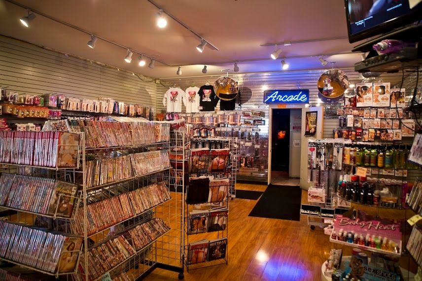 Interior of a colorful convenience store with shelves of snacks, drinks, and a glowing blue entrance sign