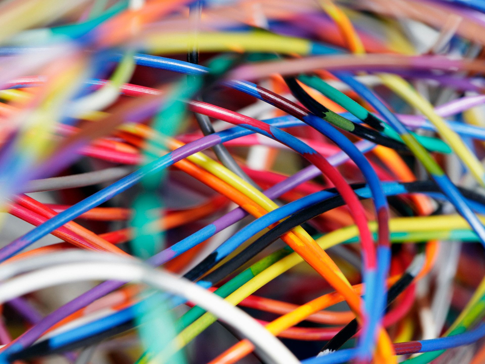 Primo piano di un aggrovigliato insieme di fili elettrici colorati, tra cui blu, rossi, gialli e verdi.
