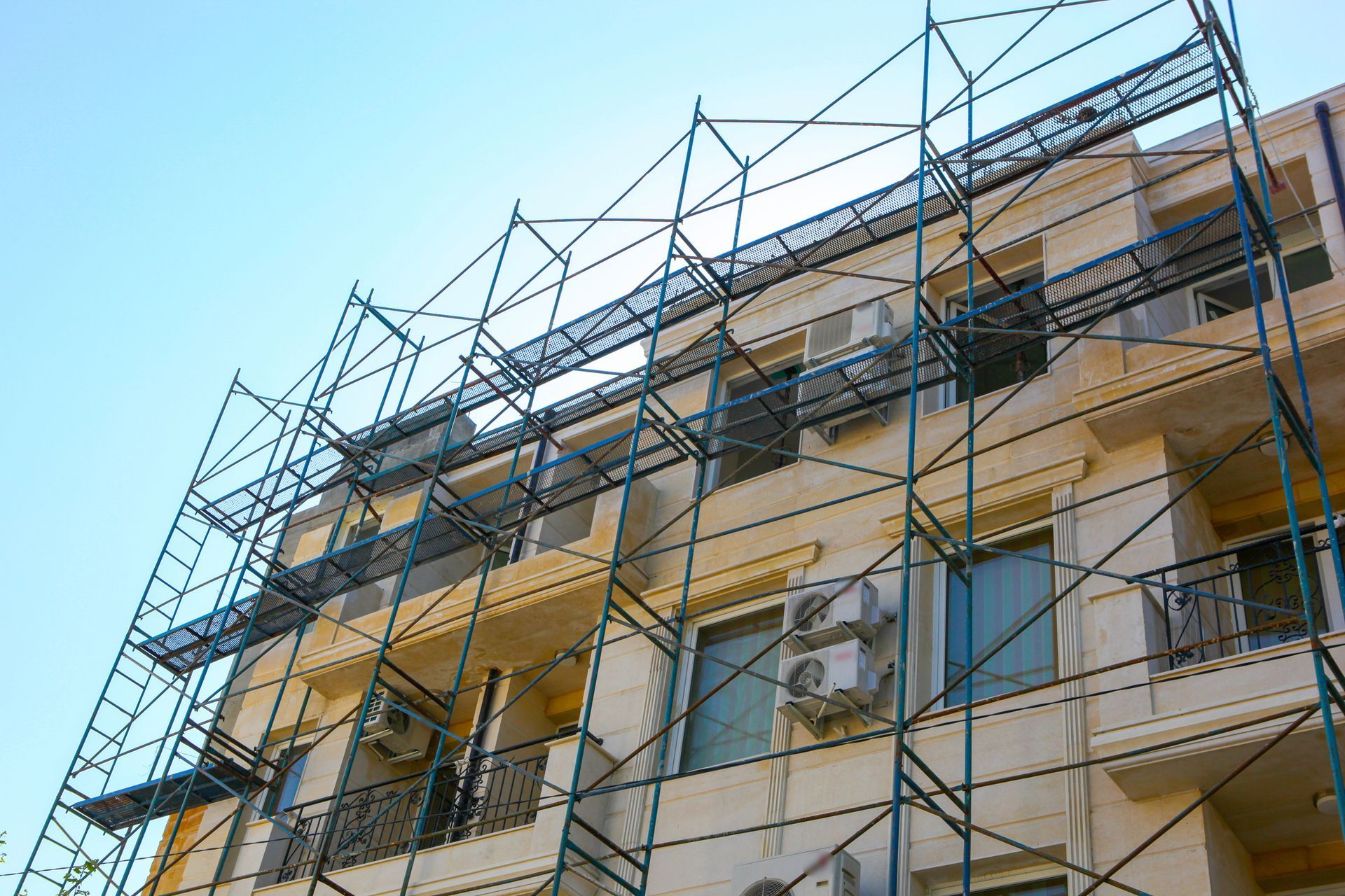 Un'impalcatura ricopre la facciata di un edificio; è visibile il cielo.