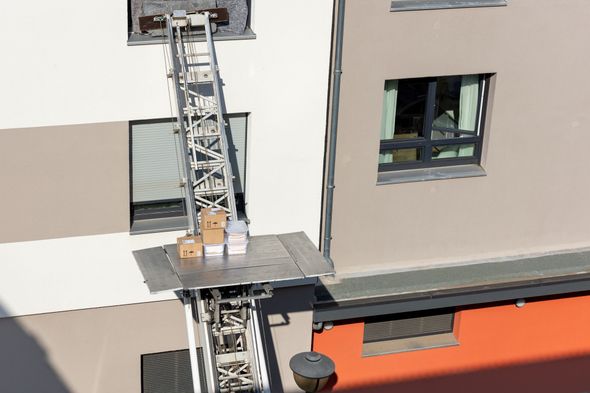 Spostamento di scatole su una piattaforma fissata a un edificio, tramite un ascensore esterno.