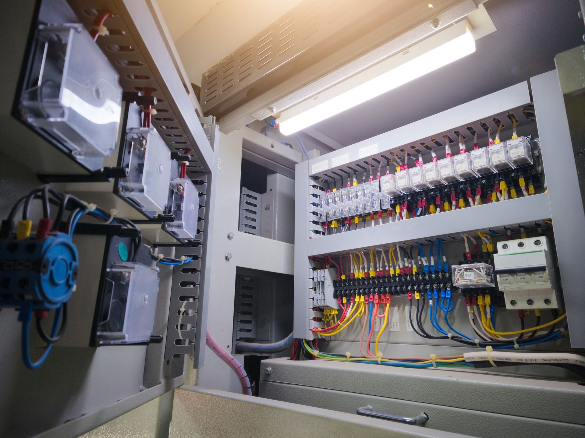 Quadro elettrico con misuratori, fili e interruttori automatici all'interno di un armadio metallico.
