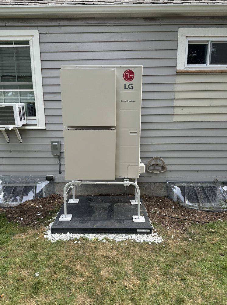 A dirty air conditioner is getting replaced outside of a house in Quincy MA.