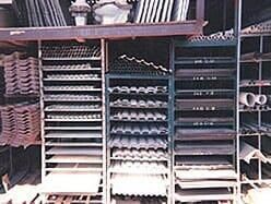 Estanterías de un almacén llenas de tubos, barras y láminas de metal de diversas formas y tamaños.