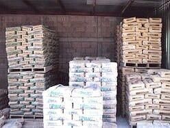 Paletas apiladas con sacos de cemento dentro de un almacén.