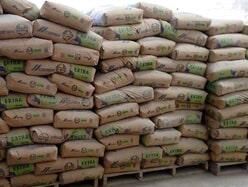 Sacos de cemento apilados sobre palets de madera en un almacén.