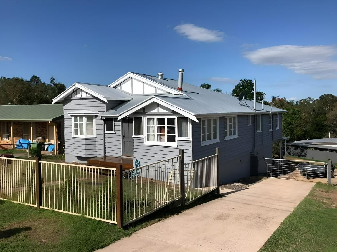 A Large House with A Fence in Front of It and A Driveway Leading to It — Allman's Painting in Monkland, QLD