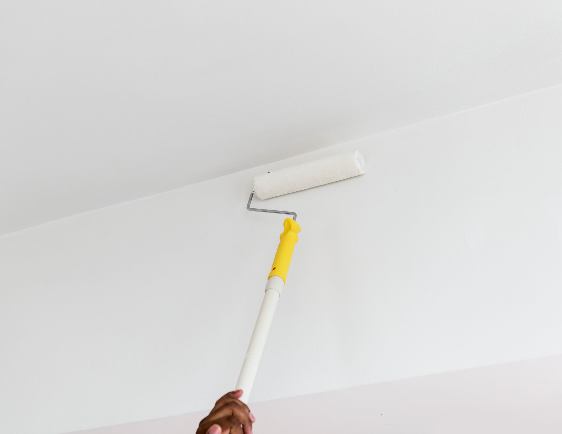 Paint Roller Being Used On A White Wall — Allman's Painting in Monkland, QLD