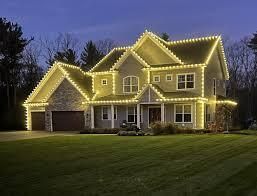 A large house with christmas lights on it is lit up at night.