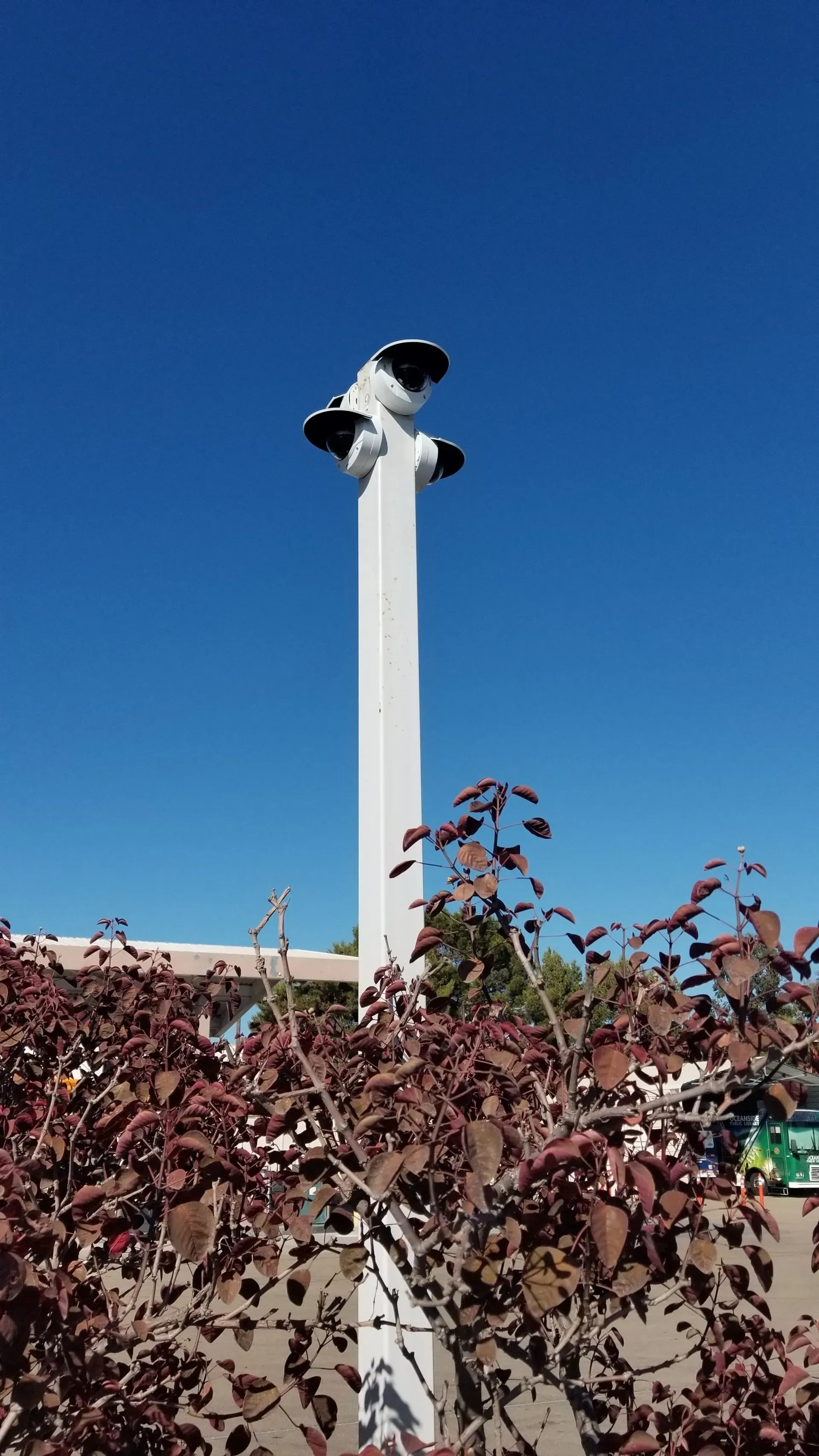 A white pole with a camera on top of it