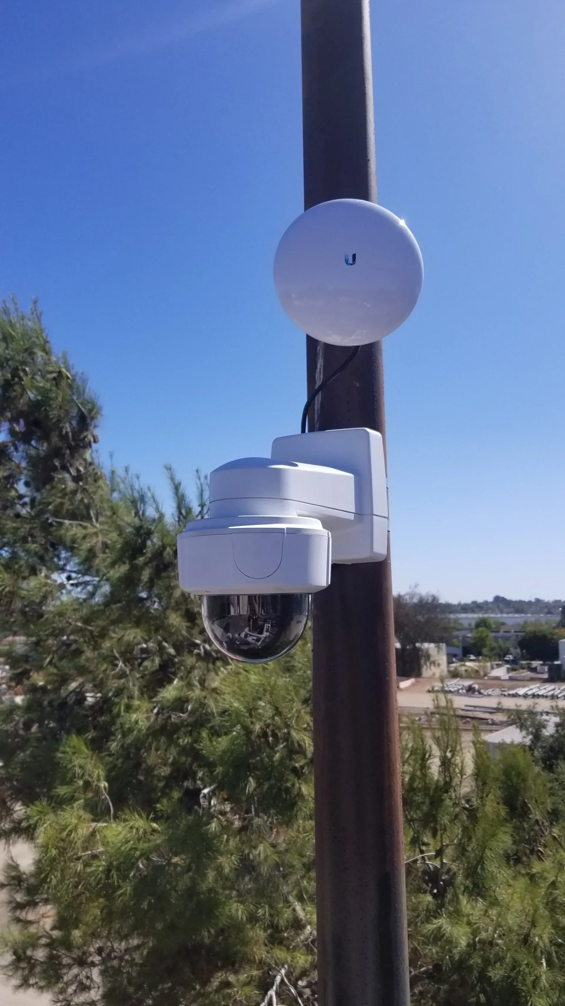A security camera is sitting on top of a pole.