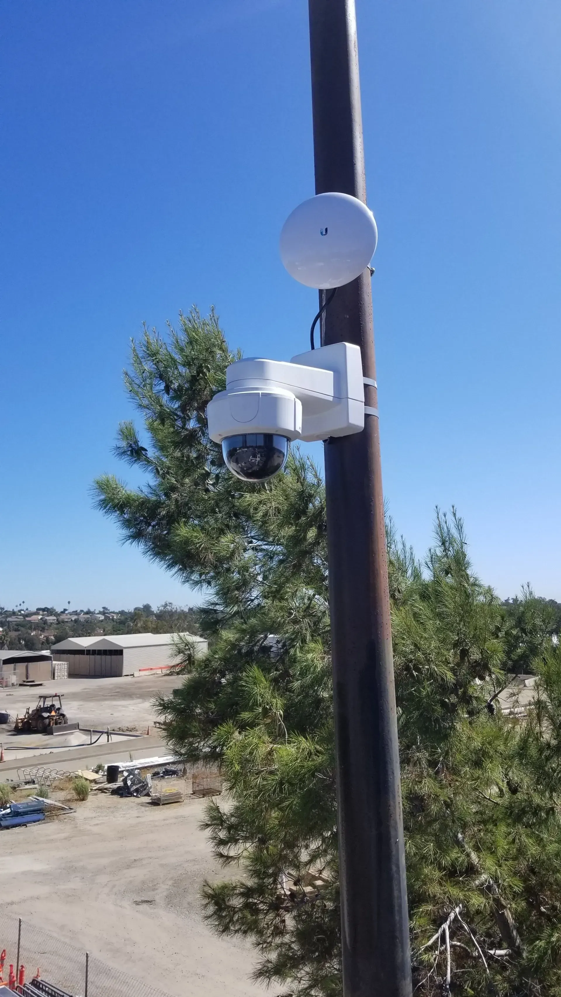 A security camera is sitting on top of a pole.