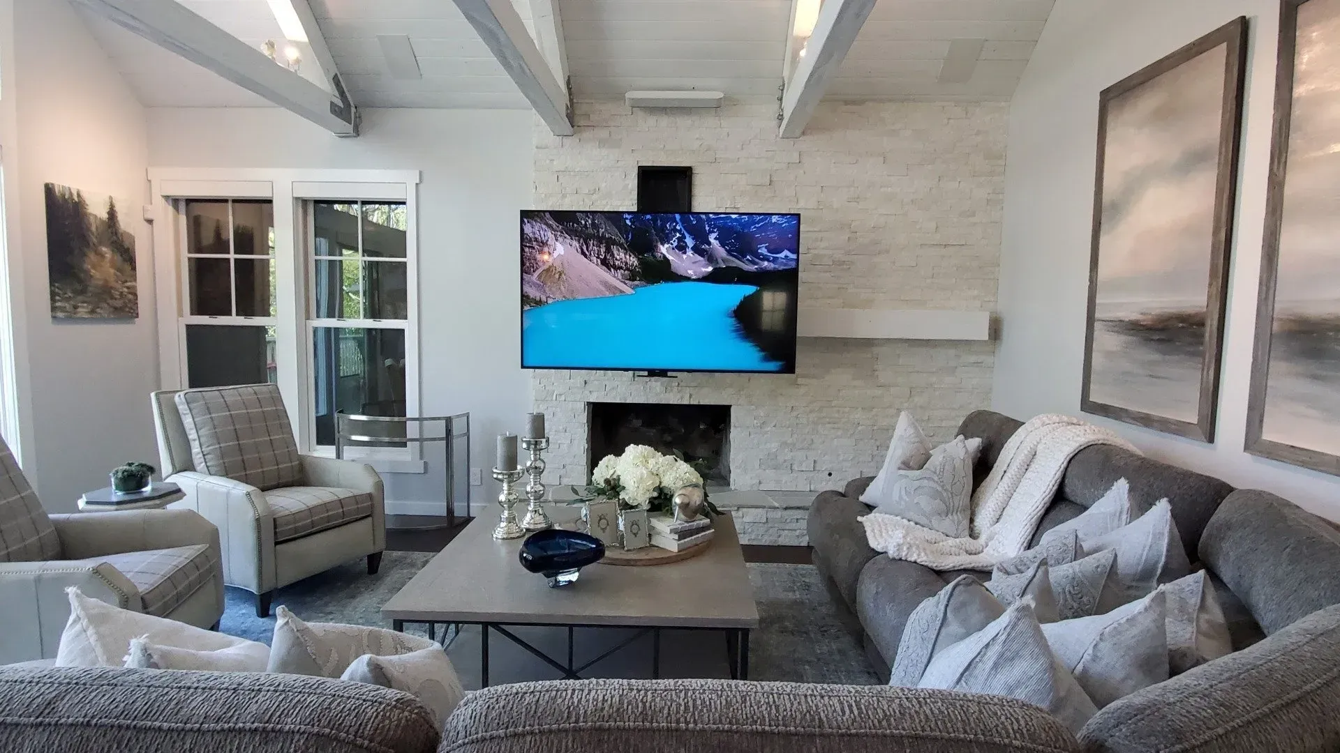 A living room with a couch , chairs , coffee table and television.