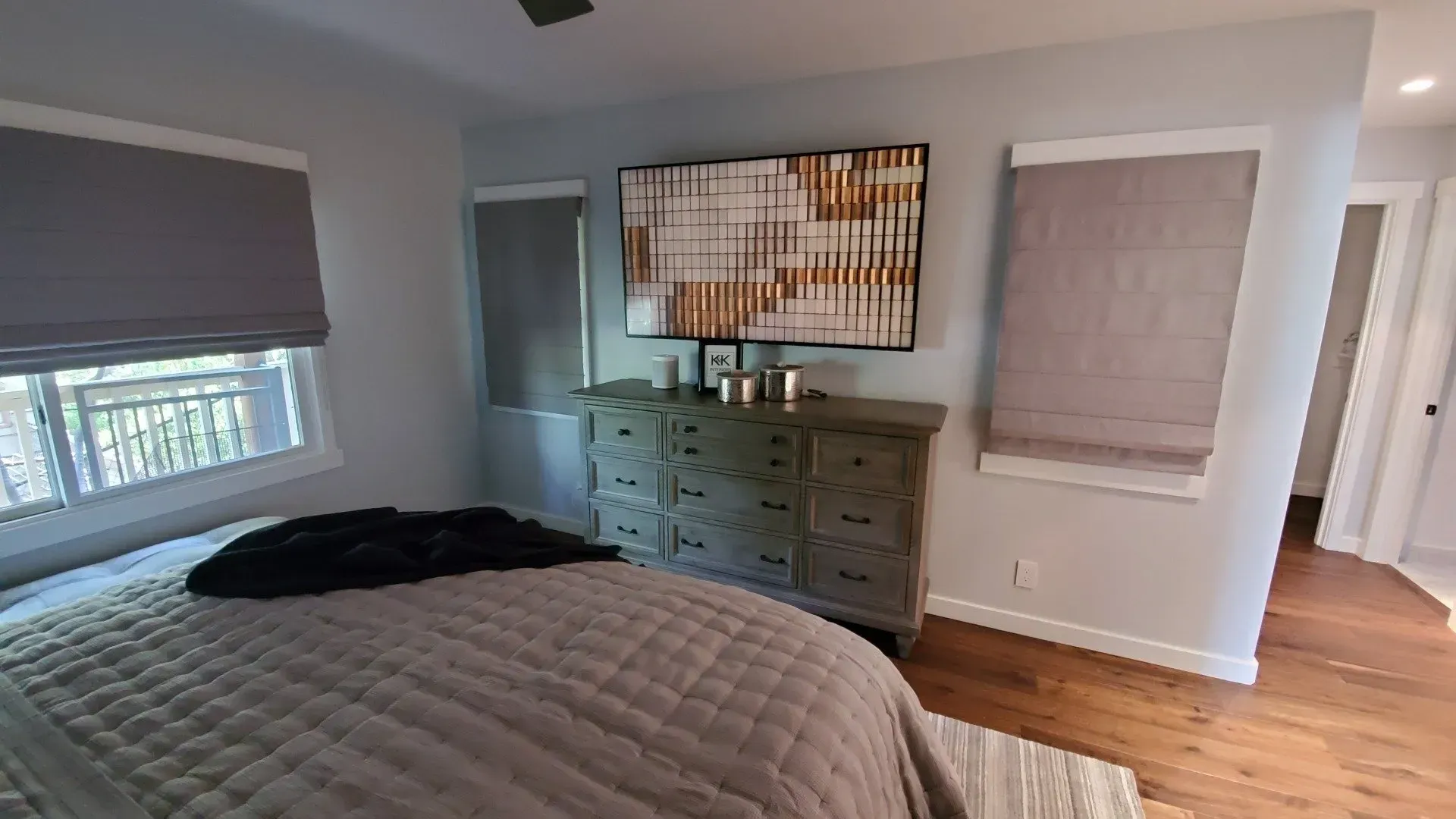 A bedroom with a bed , dresser , and painting on the wall.