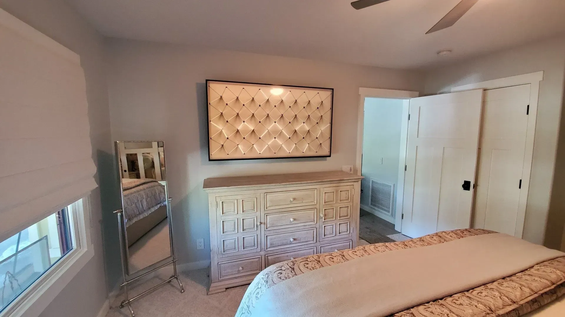 A bedroom with a bed , dresser , mirror and television.
